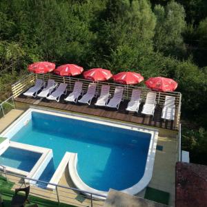 希普科沃Guest House Shipkovo Hills的一组带遮阳伞的椅子和一个游泳池