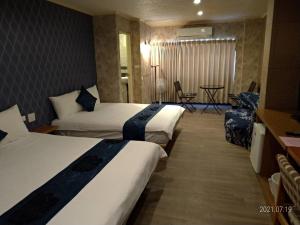 花莲市冠伦饭店的酒店客房设有两张床和一张桌子。