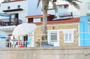 米尔托斯Myrtos Harmony Apartments的一座棕榈树和白色遮阳伞的建筑