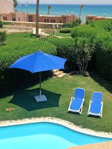 艾因苏赫纳Villa with privat pool cancun vip 36的游泳池旁的两把椅子和一把遮阳伞