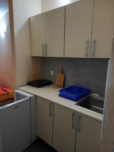 安吉MD Apartmani Canj的厨房配有白色橱柜和柜台上的蓝色容器
