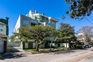 弗洛里亚诺波利斯Apto 2 Suites, Ideal Para famílias, 30m do mar的一座高大的白色建筑,前面有一棵树