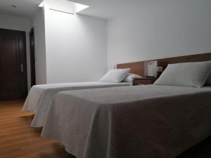 欧德鲁佐Pensión CHE的一间卧室配有两张带白色床单的床