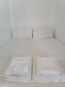 OlymposKalliopis Studio的一张白色的床,上面有3条折叠毛巾