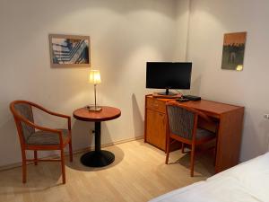 海尔巴德海利根斯塔特Passage 84 - Hotel & Café的客房设有一张桌子、一台电视和两把椅子