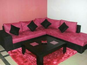 El Aouinarésidence les jardins的粉红色的沙发、黑色枕头和咖啡桌