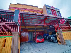 棉兰OYO 90387 Sepakat Guest House的停在大楼前的红色汽车