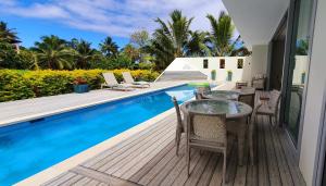 NgatangiiaMama Taras Luxury Villa的游泳池旁带桌椅的天井
