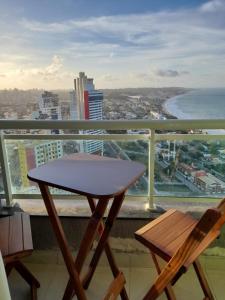 纳塔尔Ponta Negra RN01的海景阳台上配有一张桌子和两把椅子