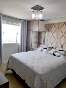 纳塔尔Ponta Negra RN01的一间卧室配有一张大床和一个吊灯。