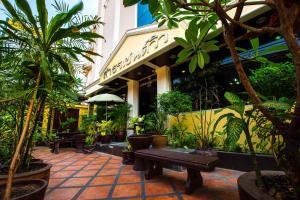 曼谷圣景服务公寓酒店的一座楼前种有植物和长凳的庭院