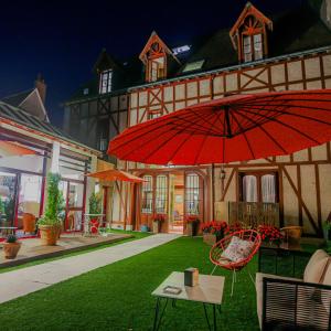 阿姆博斯魅力拉贝莱斯恩Spa酒店的一座房子,配有红色的雨伞和桌椅