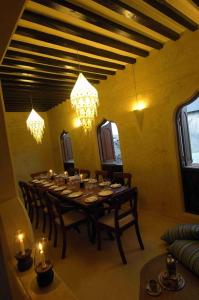 拉穆Samaki House的用餐室配有长桌子、椅子和灯
