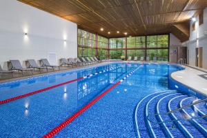 埃克塞特Woodbury Park Hotel & Spa的大型建筑内的大型游泳池,配有椅子