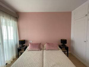 阿罗纳Playa de las Vistas Los Cristianos WIFI BEACH VIEW的卧室配有一张带粉红色枕头的大床