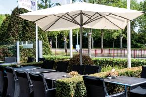 米德尔堡Fletcher Hotel-Restaurant Arneville-Middelburg的一张带白色遮阳伞和黑色椅子的桌子