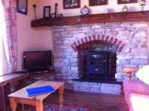 福克斯福德The Stables - 200 Year Old Stone Built Cottage的客厅设有石制壁炉和电视