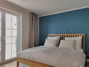 普特布斯Jolle 54的一间卧室拥有蓝色的墙壁,配有一张带白色枕头的床。