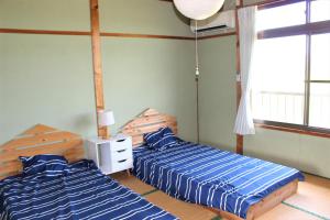 壹岐市ikibase Guest House的一间卧室设有两张床和窗户。