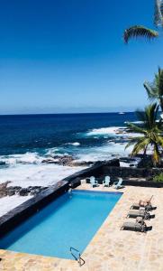 科纳Kona Tiki Hotel的一个带椅子的游泳池以及大海