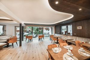 塞尔瓦迪加尔代纳山谷Garni Hotel Miara - Your Dolomites Home的餐厅设有木桌、椅子和窗户。