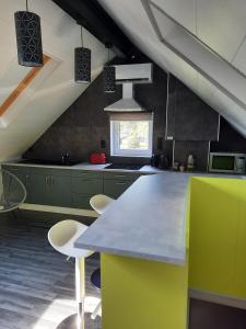 Braine-le-ComteStudio neuf côté campagne agréable à vivre.的厨房配有绿色橱柜和带椅子的柜台。