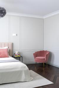 维尔纽斯Place No. 2的一间卧室配有一张床和一张粉红色的椅子