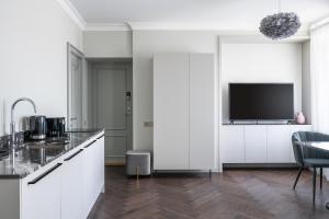 维尔纽斯Place No. 2的厨房配有白色橱柜和平面电视。