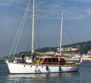 多维尔Port Deauville Yacht vintage的一条白船在水里,上面的人在