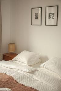 WieleńPrzytulny Apartament Mickiewicza 14/5的一张白色的床,墙上有两张照片