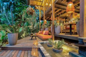 别霍港aWà Beach Hotel的木甲板上种有植物和沙发的天井