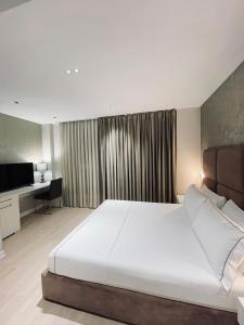 地拉那奥雷斯蒂中心酒店的卧室配有一张白色大床和一张书桌