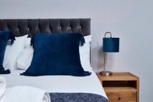 达宁顿堡Delven House, Apartment 5的一间卧室配有一张带蓝色枕头和一盏灯的床。