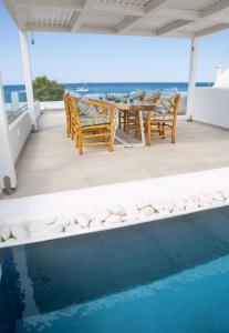 维查德Aegean Melody Suites & Villas的游泳池旁带桌椅的天井