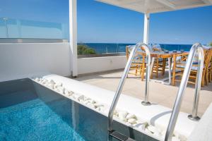 维查德Aegean Melody Suites的阳台设有小型游泳池、桌子和椅子。