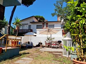 利多迪卡马约雷Villa Versilia的庭院配有桌椅和遮阳伞。