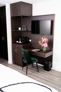 卡尔本Luxstay Karben - Self-Check-In的客房设有书桌、电视和绿椅