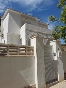 贝尼多姆Casa MYA con terreno privado y parking compartido - a 800m de Playa Poniente的白色的房子,有门和栅栏