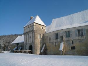 蒙特雷索Chateau-monastère de La Corroirie的一座古老的石头建筑,地面上积雪