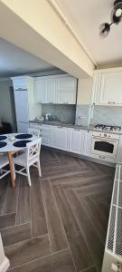阿尔杰什河畔库尔泰亚White rezidence的一间大厨房,配有白色的橱柜和一张桌子