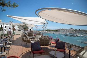 特拉尼Ognissanti Restaurant Spa Hotel Rooftop的一个带桌椅的甲板,享有码头的景色