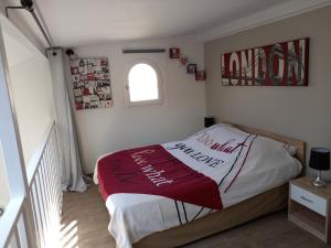 马恩河畔的尚格尼STUDIO PROCHE PARIS ET DISNEYLAND PARIS的一间卧室配有一张带红白毯子的床