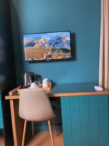 库塔伊西Green Rooms的一张桌子、椅子和墙上的电视
