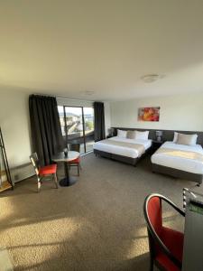 基督城Carnmore Hagley Park的酒店客房带两张床和一张桌子以及椅子。