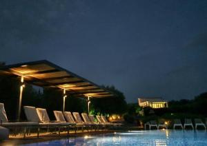 瓦西利基Villa Del Mar的一群椅子在晚上坐在泳池旁