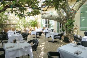 奥朗日Logis hôtel restaurant de Provence的一间设有白色桌椅和树的餐厅