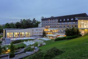 维尼Hotel Sitno Forest Resort的一座带白色桌子的庭院的大型建筑