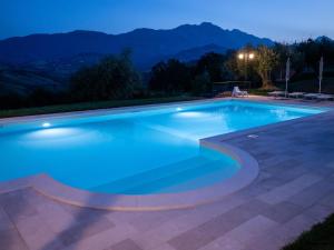 Castiglione Messer Raimondoagriturismo borgo del ginepro的一座晚上拥有山脉背景的游泳池
