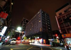 台北沃客商旅 - 三重馆的夜幕降临的城市街道上一座高楼
