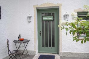 若特阿赫-埃根阿多连娜别墅酒店的通往白色建筑的绿色门,配有桌子